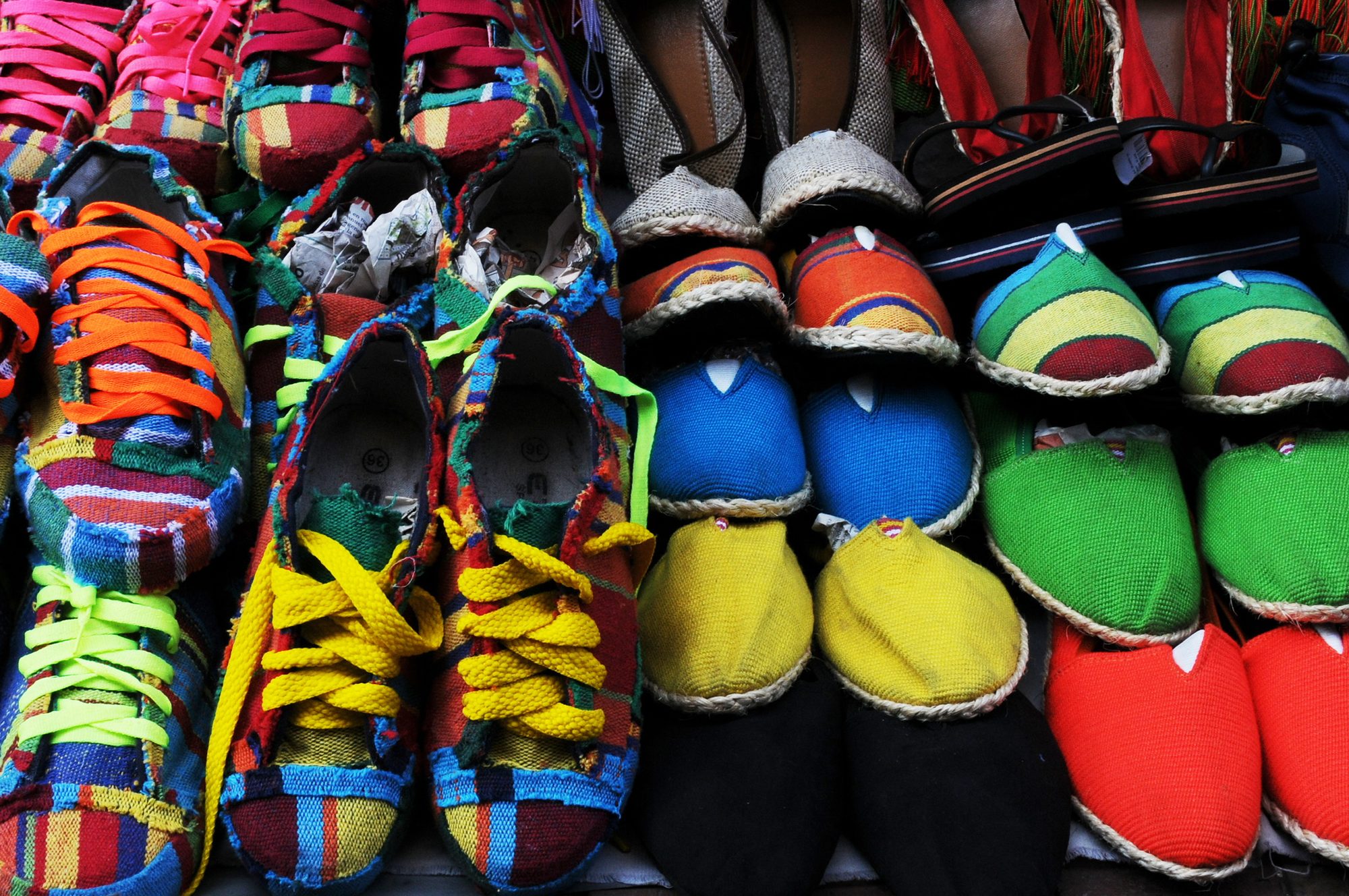 Rows of brightly coloured canvas shoes stacked at a market stall, Cartagena, Colombia — photograph by Brian Walker