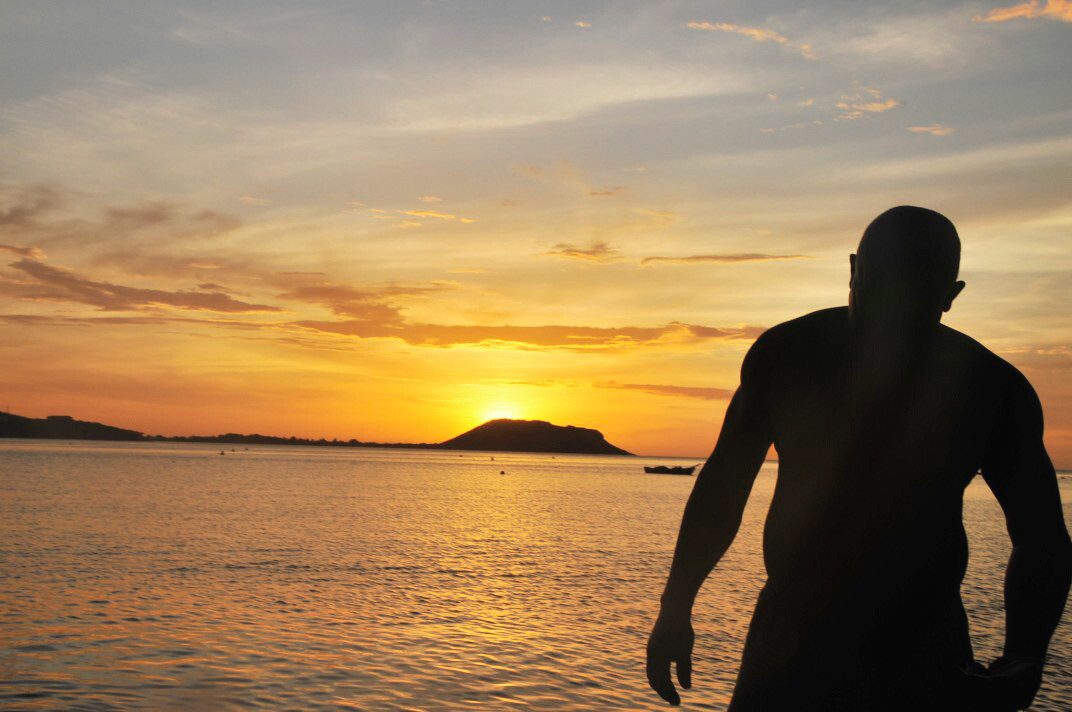 A man silhouetted against the sea at sunset, Saint Vincent — photograph by Brian Walker