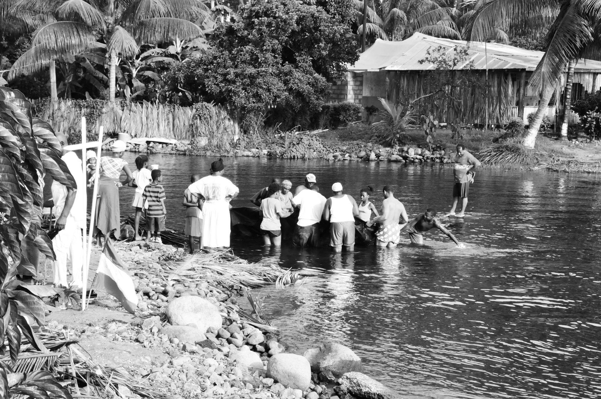 A riverside baptism, a congregation dressed in white gathered at the water's edge, black and white — photograph by Brian Walker